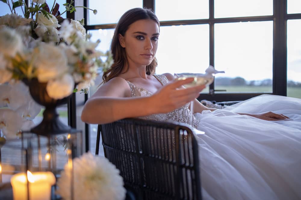 Glamourous wedding dress bride drinking champagne modern bridal makeup with nude lips