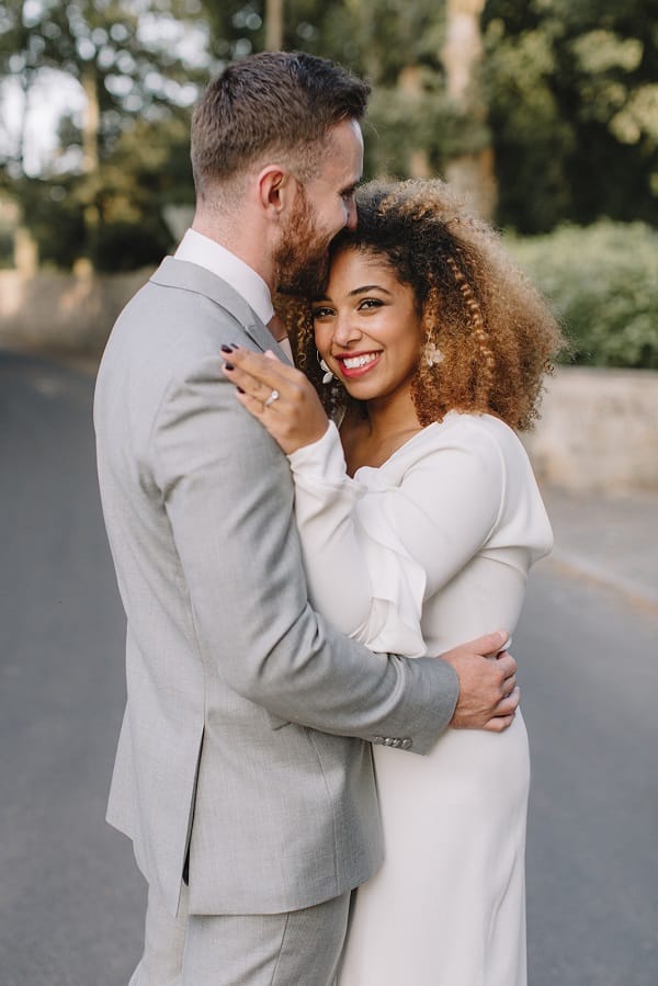 Bride and groom embracing themselves bride with naturally curly hair wearing natural makeup with red lips